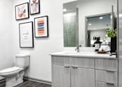 Thumbnail 10 of 35 - A bathroom with a toilet, sink, and framed pictures on the wall.